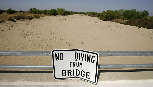 New York Times - dry river-bed with No Diving sign on bridge